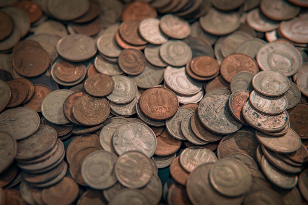 A scattered collection of various vintage coins with copper and silver tones, depicting wealth and currency.